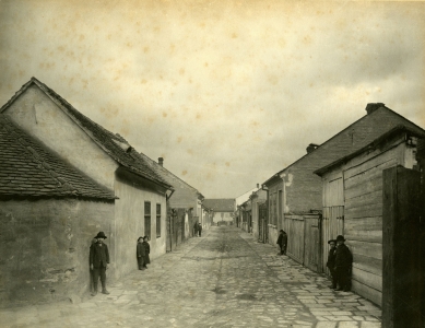 Nájemní dům Anny Siebenscheinové - Pohled do dělnické kolonie Köffilerovy manufaktury z míst současného křížení ulic Mášovy a Mezírky, 1907. Budova v pozadí je hlavní tovární budova stojící v místě nynějšího hotelu Passage. Zdroj AMB