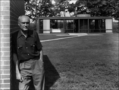 The Glass House - Philip Johnson leaning against the guest house made of rough masonry.