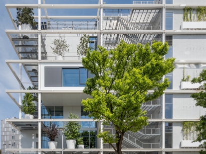 No "blue box" - The new building is surrounded on all sides by a steel structure with a depth of 4.5 meters, creating the impression of shelves. It includes escape stairs, balconies lined with trees, and bay windows with large glazed fronts. For the façade, the architects chose the Schüco FWS 50.SI column-and-beam system.