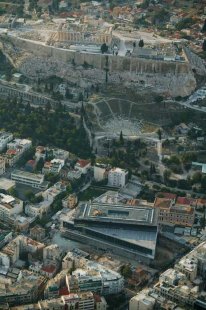 Věda, architekti a památky - <B>Athény</B>: Nové akropolské muzeum (2003-08) podle návrhu Američana švýcarského původu Bernarda Tschumiho je situováno pod posvátným pahorkem, mezi zástavbou drobného měřítka na okraji jediné dochované historické městské čtvrti Plaka. Velký lichoběžníkový hranol z betonu, skla a mramoru, na pilotech vyzdvižený nad svažitý terén, se okny otevírá směrem k Akropoli. - foto: 2007, online, www.newacropolismuseum.gr/eng/photos/index.htm (25.3.2008)
