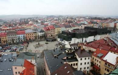 Věda, architekti a památky - <B>Regenerace a dialog počesku</B>: Zdeněk Sklepek, obchodní dům Prior, Jihlava, 1978-83, foto 2008. Nositel titulu CSc. rozčlenil hmoty pomocí „domovních“ oken a falešných střech tak dětinsky, až se pozorovateli téměř nechce věřit, že za tím nestojí nějaký obzvlášť rafinovaný koncept. Možná první příklad tzv. podnikatelského baroka u nás. Stromy zbytečně zakrývají historické fasády, zatímco obchodní dům a zásobovací rampy rozrývající povrch náměstí zůstávají odkryté. - foto: Martin Horáček
