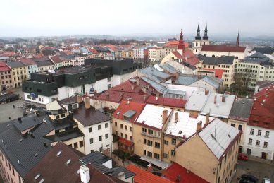 Věda, architekti a památky - <B>Regenerace a dialog počesku</B>: Zdeněk Sklepek, obchodní dům Prior, Jihlava, 1978-83, foto 2008. Nositel titulu CSc. rozčlenil hmoty pomocí „domovních“ oken a falešných střech tak dětinsky, až se pozorovateli téměř nechce věřit, že za tím nestojí nějaký obzvlášť rafinovaný koncept. Možná první příklad tzv. podnikatelského baroka u nás. Stromy zbytečně zakrývají historické fasády, zatímco obchodní dům a zásobovací rampy rozrývající povrch náměstí zůstávají odkryté. - foto: Martin Horáček